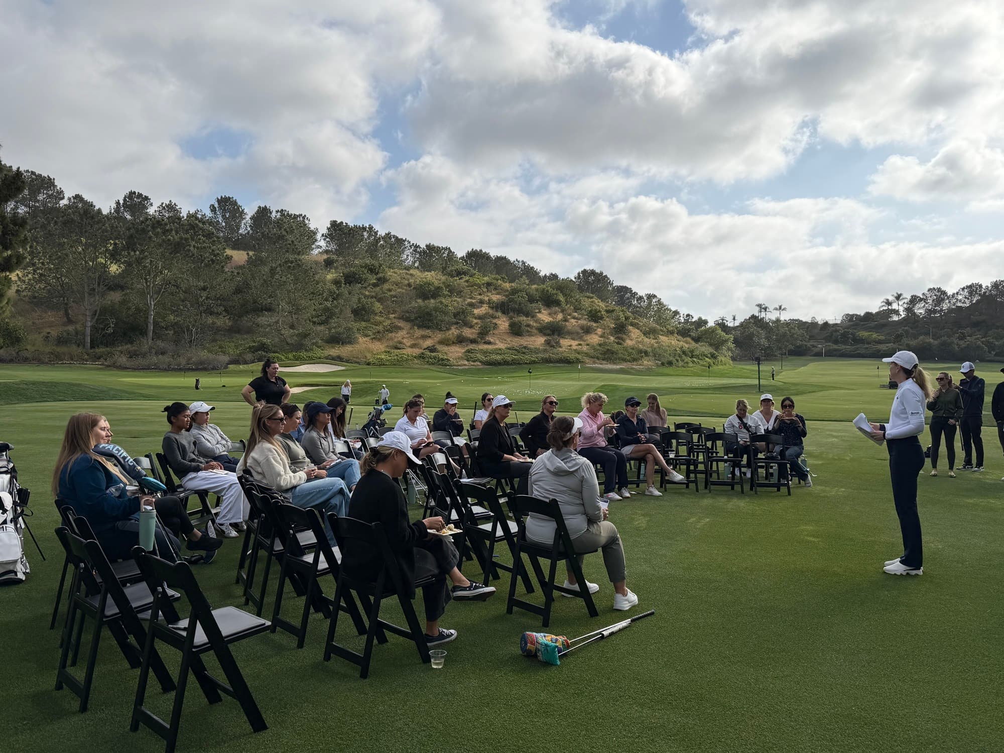 Shannon teaching a seated audience of golfers on the course